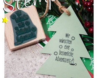 May include: A green Christmas tree-shaped card with the text "Wir wünschen eine besinnliche Adventszeit" in black. The card is on a red and green striped background with a wooden stamp with a snowflake design.