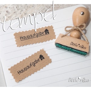 Könnte beinhalten: Ein Stempel aus Holz mit dem Text "little nika" und einem Haussymbol. Der Stempel wird verwendet, um ein braunes Papieretikett mit dem Text "Hausaufgabe" und einem Haussymbol zu erstellen.
