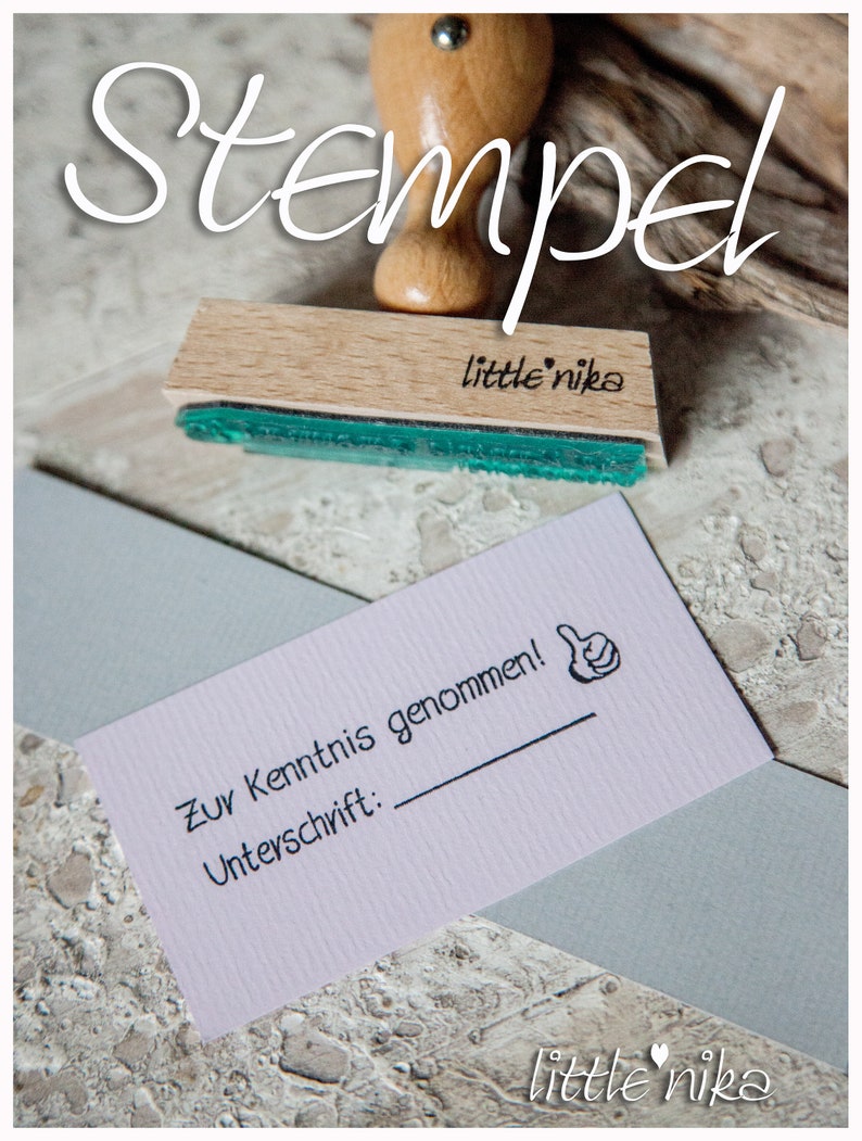 May include: A wooden stamp with the text "little nika" on it. The stamp is used to create a thumbs up image with the text "Zur Kenntnis genommen!" and "Unterschrift:" on a white card.