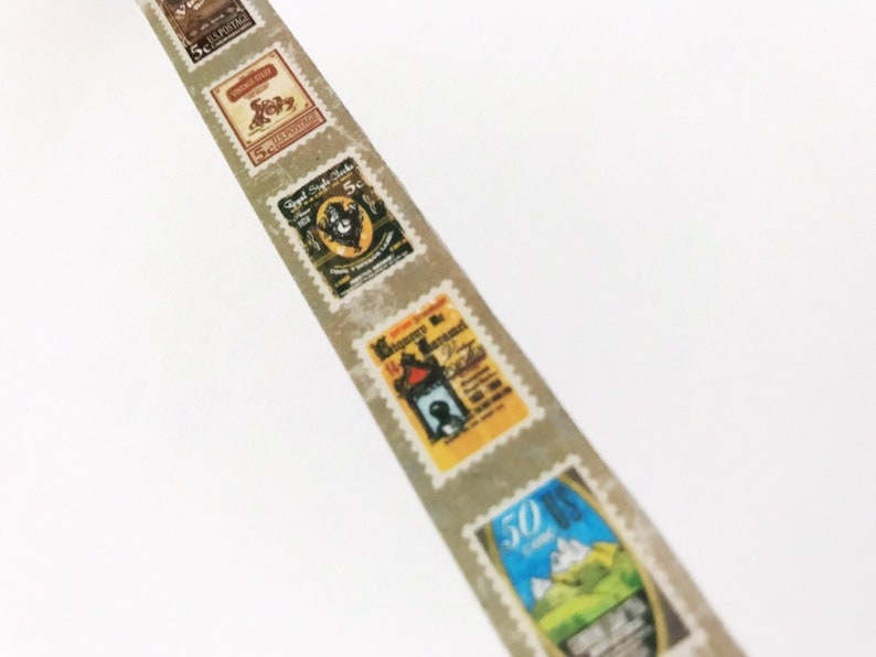 May include: A strip of washi tape featuring vintage postage stamp designs. The stamps are in various colors, including brown, yellow, and blue, with text and illustrations. The tape has a light gray background and a serrated edge.