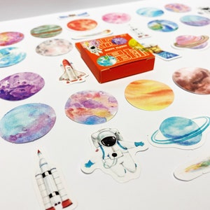Mini pegatinas espaciales en una caja de almacenamiento: 45 pegatinas de planetas, cohetes y astronautas para diarios, manualidades, álbumes de recortes, agendas y diarios.