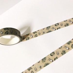 May include: A roll of brown washi tape with a repeating pattern of green leaves and black and white beetles.