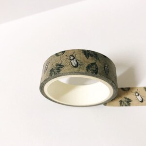 May include: A roll of brown washi tape with a repeating pattern of green leaves and black beetles.