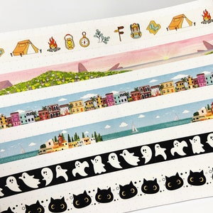 May include: A collection of six colorful washi tapes featuring various designs, including a camping scene, a cityscape, a seascape, ghosts, and cats. The tapes are all on a white background.