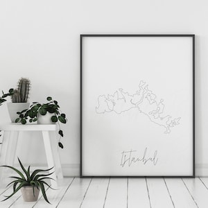 以下が含まれることがあります： イスタンブールの白黒ラインアートプリント。都市の地理をミニマルに表現したアウトラインと、筆記体で書かれた都市名が特徴です。明るくミニマルなインテリアに飾られています。