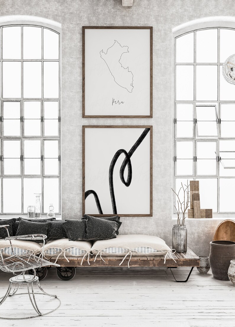 May include: Two framed art prints on a wall. The top print is a line drawing of Peru with the name "Peru" below. The bottom print features a black abstract line on a white background. The room has large windows.