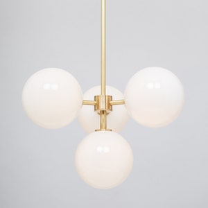 May include: A brass and white glass chandelier with four globe-shaped lights.