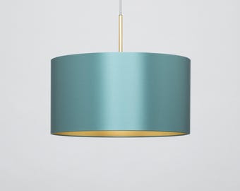 May include: A teal pendant light with a gold trim and a white cord.