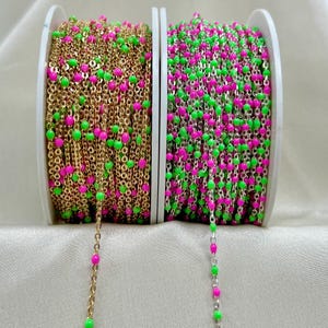 May include: Two spools of chain with alternating pink and green beads. The chain on the left is gold, and the chain on the right is silver.