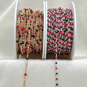 May include: Two spools of chain with red and black beads. The chain on the left is gold and the chain on the right is silver.
