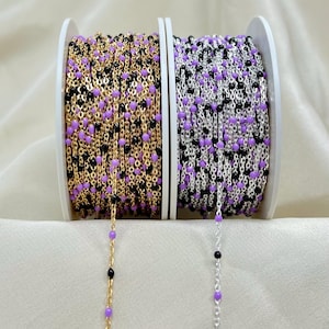 May include: Two spools of chain with purple and black beads. The chain on the left is gold and the chain on the right is silver.
