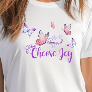 May include: White t-shirt with a purple and pink butterfly design and the text "Choose Joy".