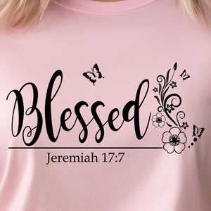 May include: Pink t-shirt with a black graphic that says "Blessed" with a floral design and butterflies. The text "Jeremiah 17:7" is below the graphic.