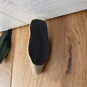 May include: A beige and black shoe sole with a textured surface.