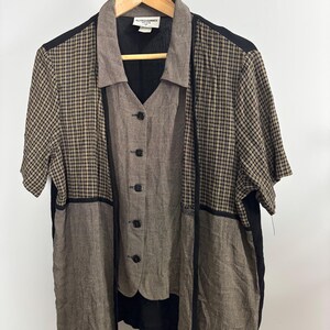 Può includere: Un completo da donna a due pezzi con una giacca a maniche corte e aperta sul davanti e un gilet abbottonato. La giacca presenta un motivo a quadri marrone e beige sulle maniche e sulla parte superiore della schiena, con pannelli marroni a tinta unita e finiture nere. Il gilet è marrone tinta unita.