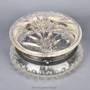 May include: A clear glass trinket box with a silver band around the lid. The lid is decorated with a floral pattern.