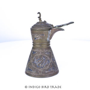 May include: An antique brass coffee pot with a blue and gold floral design. The pot has a spout and a handle, and the lid has a crescent moon finial.