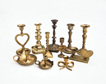May include: A collection of 10 brass candle holders in various styles, including heart-shaped, round, and square bases. Some candle holders have a simple design, while others feature intricate details.