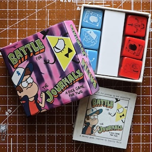 Könnte beinhalten: Brettspiel "Battle for the Journals" mit einer rosa-violetten Schachtel mit Cartoon-Figuren. Das Set enthält blaue und rote Würfel mit Symbolen und ein kleines Heft. Das Spiel ist für zwei Spieler.
