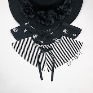 May include: Two black and white striped fabric collars with a black ribbon tie. The top collar has a skull print. The text "ELIXIRLAH" is visible on the bottom collar.