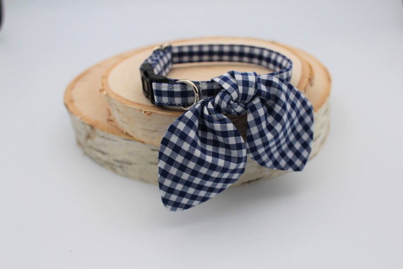 K&ouml;nnte beinhalten: Ein blaues und wei&szlig;es Gingham-Hundehalsband mit einer Schleife. Das Halsband liegt auf einer Holzoberfl&auml;che.
