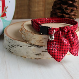 May include: Red and white snowflake patterned cat collar with a bell and a bow tie.