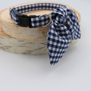 K&ouml;nnte beinhalten: Ein blaues und wei&szlig;es Gingham-Hundehalsband mit passendem Fliege. Das Halsband ist verstellbar und hat eine Metallschnalle.