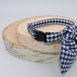 K&ouml;nnte beinhalten: Ein blaues und wei&szlig;es Gingham-Hundehalsband mit einer schwarzen Schnalle und einer passenden Schleife.