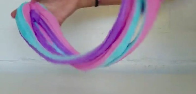 May include: A close-up of a multi-colored slime being stretched and pulled. The slime is pink, purple, and blue.