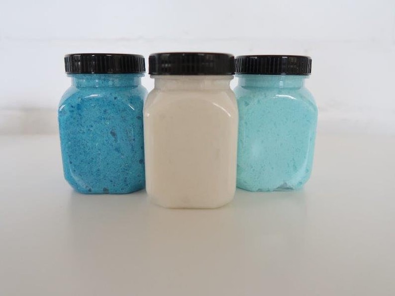 May include: Three glass jars with black lids filled with blue, white, and light blue bath salts.