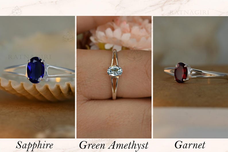 May include: Three silver rings with oval gemstones: a deep blue sapphire, a light blue green amethyst, and a dark red garnet. The rings are displayed against neutral backgrounds. Text at the bottom reads "Sapphire", "Green Amethyst", and "Garnet".