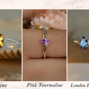 May include: Three rings with oval gemstones: a yellow citrine, a pink tourmaline, and a London blue topaz. Each ring has a silver band. The text below the rings reads "Citrine", "Pink Tourmaline", and "London Blue Topaz".