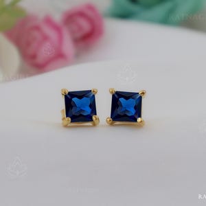 May include: A pair of gold stud earrings with square blue gemstones.