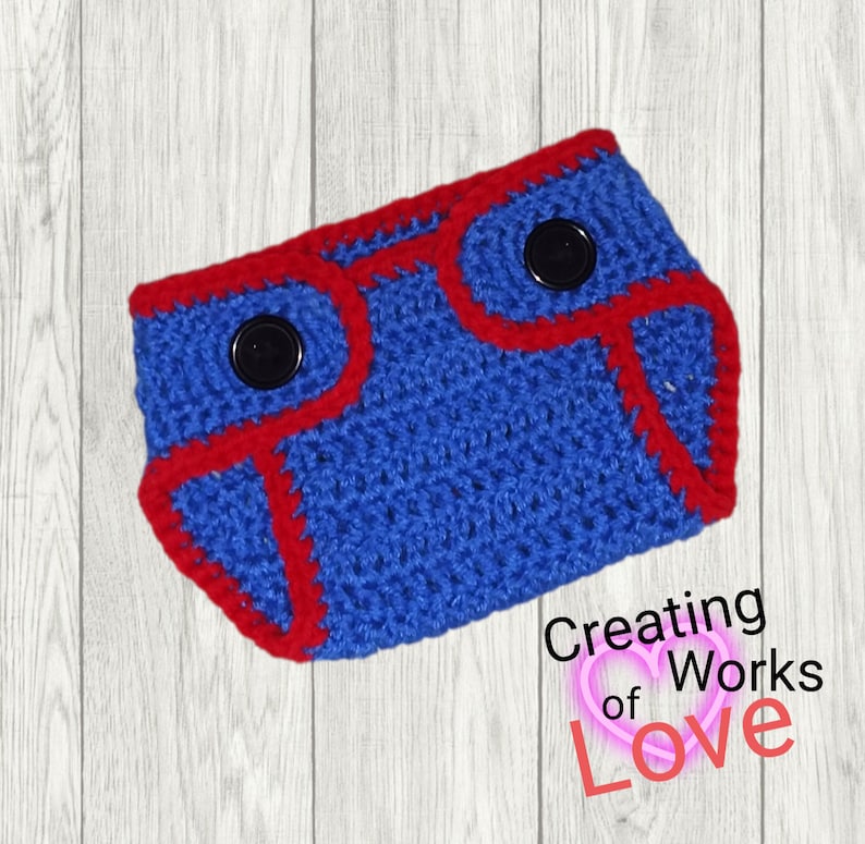 Puede incluir: Cubierta de pa&ntilde;al para beb&eacute; de crochet azul con ribete rojo y dos botones negros.