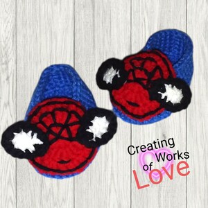 Puede incluir: Un par de botines de beb&eacute; de crochet azul y rojo con un dise&ntilde;o de Spiderman. Los botines tienen un dise&ntilde;o de telara&ntilde;a blanca y negra en la parte delantera y ojos blancos y negros en los lados.