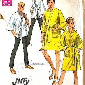 May include: A Simplicity 8256 sewing pattern envelope featuring illustrations of two robe styles. One style is a white wrap jacket with a patterned border and tie belt, and the other is a solid yellow knee-length robe with a tie belt and pockets.