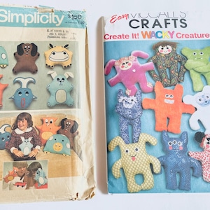 May include: Two vintage sewing pattern packets. The Simplicity pattern features stuffed animal designs, including a turtle, dog, and cow. The Easy Vical Craft pattern features various "Wacky Creatures" in bright colors.