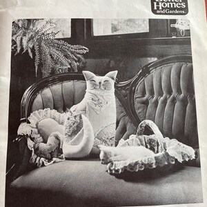 K&ouml;nnte beinhalten: Schwarz-Wei&szlig;-Bild eines Patchwork-Katzenmusters. Die Katze sitzt auf einem Vintage-Stuhl mit anderen Katzen-Themen-Artikeln. Der Text "FANCY PATCHWORK CAT PATTERN" steht oben. Die fertige Gr&ouml;&szlig;e betr&auml;gt ca. 46 cm hoch.