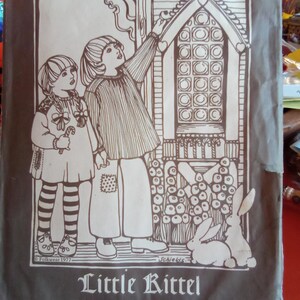 May include: A vintage Folkwear pattern envelope, featuring a black and white illustration of two children looking at a decorative house with a rabbit. The text includes "Folkwear," "Ethnic Patterns," "110," and "Little Kittel."