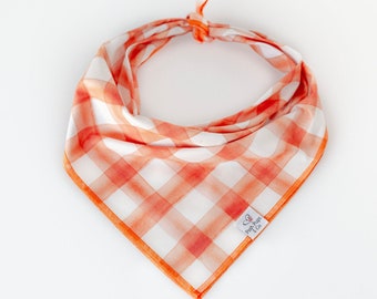 May include: Orange and white gingham dog bandana with a "Posh Pupps & Co." label.