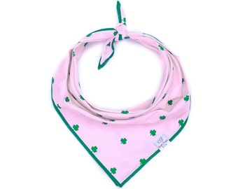 May include: Pink dog bandana with a green shamrock pattern and a green border. The bandana has a small white tag with the text "Pawty Paws Co."