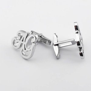 May include: Silver cufflinks with the initials "AG" in a cursive font.