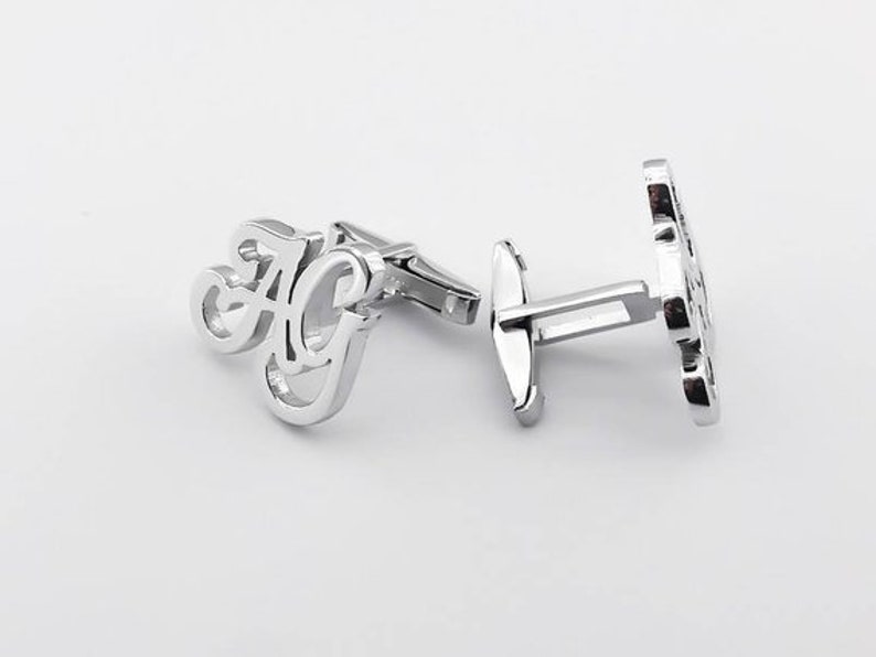May include: Silver cufflinks with the initials "AG" in a cursive font.