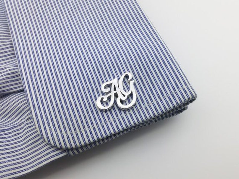 May include: Silver cufflinks with the letters "AG" in a stylized font.
