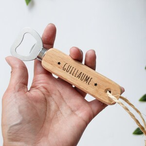 Peut inclure: Un ouvre-bouteille en bois avec un ouvre-bouteille en métal et une ficelle attachée. Le manche est gravé du nom "Guillaume" et de deux étoiles.