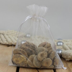 May include: A white organza bag filled with a variety of brown, irregularly shaped stones. The bag is tied with a white ribbon.