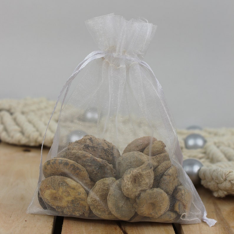 May include: A white organza bag filled with a variety of brown, irregularly shaped stones. The bag is tied with a white ribbon.