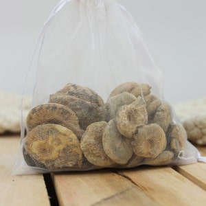 May include: A white mesh bag filled with a variety of light brown, smooth, round stones.
