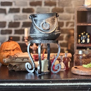 Könnte beinhalten: Ein Miniatur-Hexenkessel auf einem dekorativen Ständer, mit einem geschnitzten Kürbis, Schriftrollen und Zaubertränken. Ein kleines Holzregal zeigt Flaschen und Gläser. Die Szene erinnert an Halloween oder ein Fantasy-Thema.