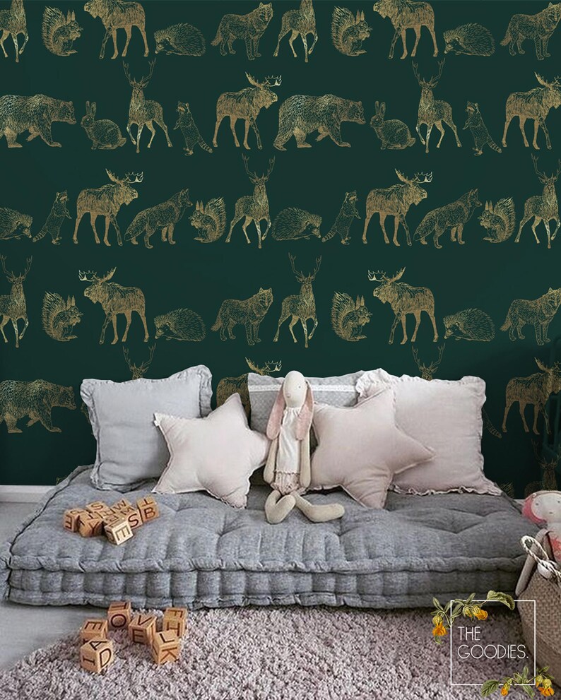 May include: A green and gold wallpaper with a repeating pattern of woodland animals. The animals include deer, moose, bears, wolves, squirrels, and raccoons. The wallpaper is shown in a nursery setting with a gray futon and pillows.